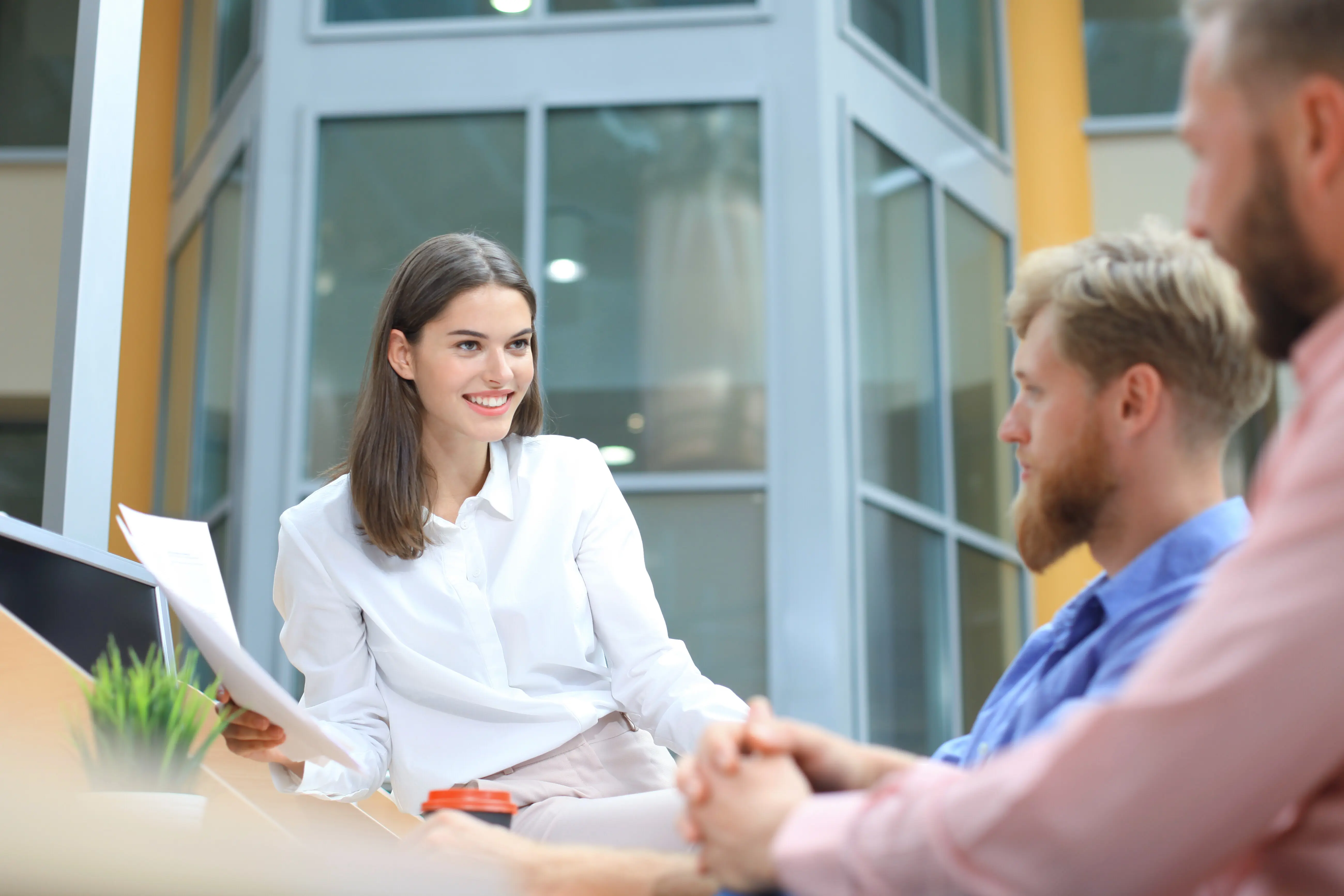 Eine Gruppe junger, moderner Menschen in Smart-Casual-Kleidung hält im kreativen Büro stehend eine Brainstorming-Sitzung ab.