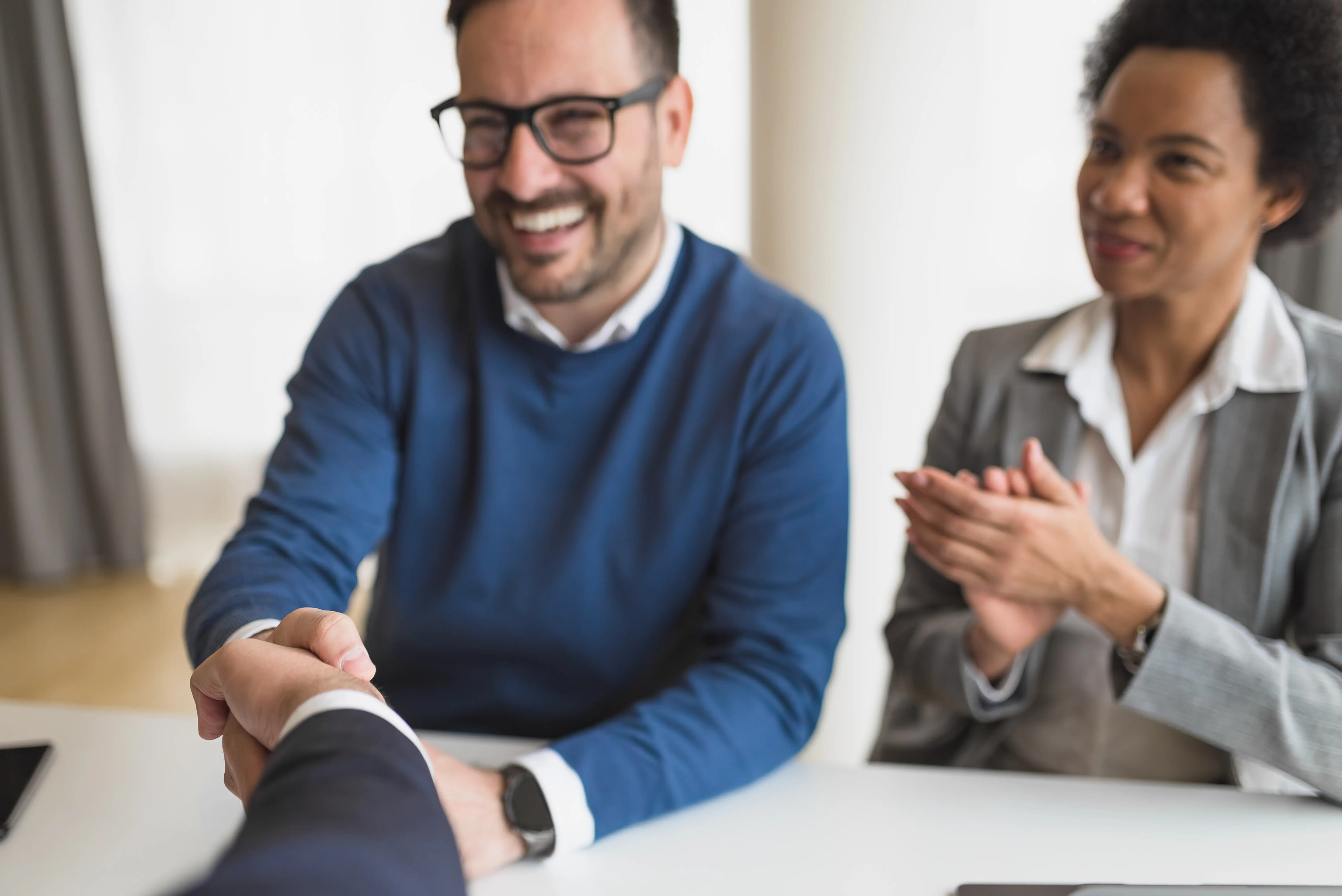 Zwei unterschiedliche Partner freuen sich über ihren Geschäftsabschluss mit einem Kunden.